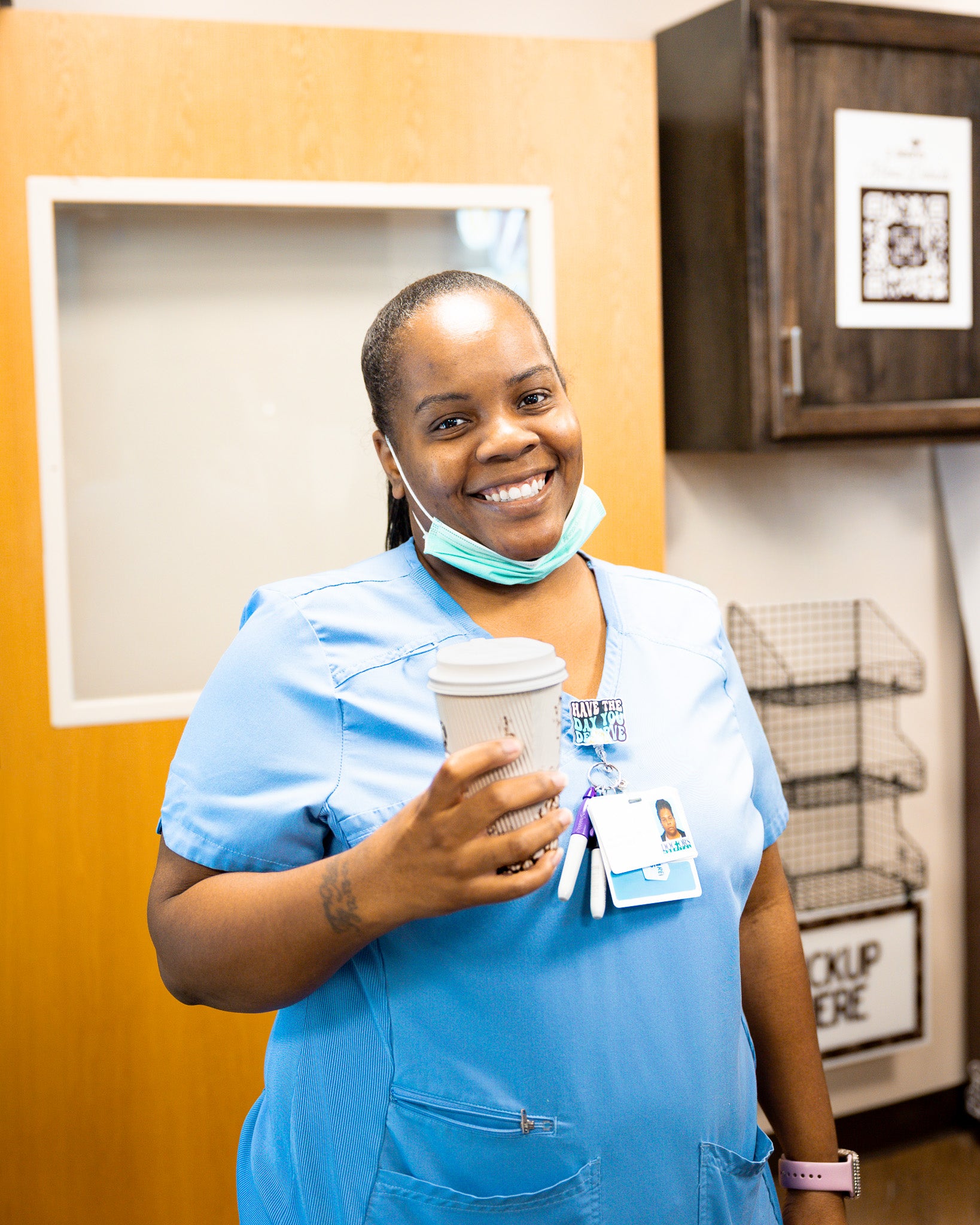 Nurse in blue scrubs holding a coffee cup in a hospital cafe setting