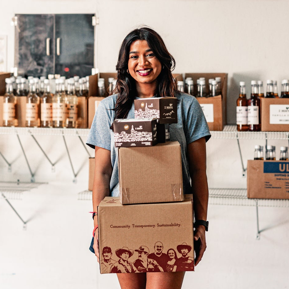 Woman holding a stack of boxes with products in the background