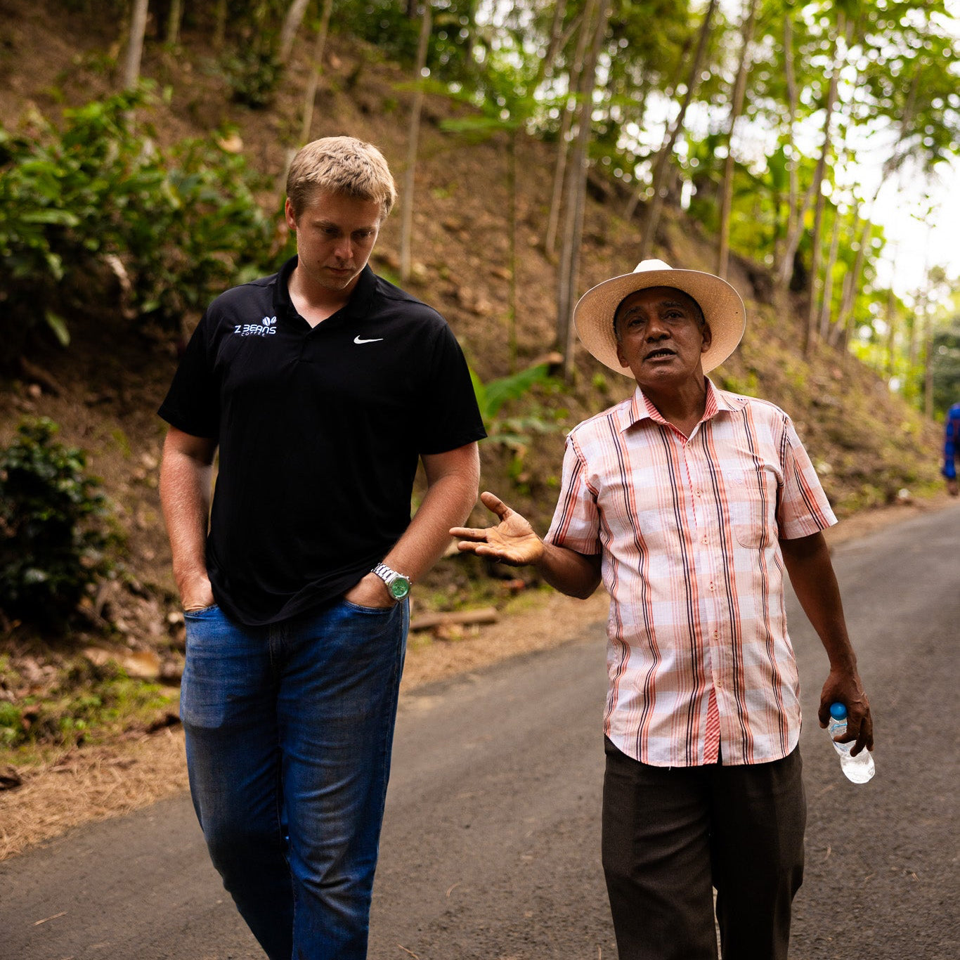 Two men walking on a road surrounded by greenery