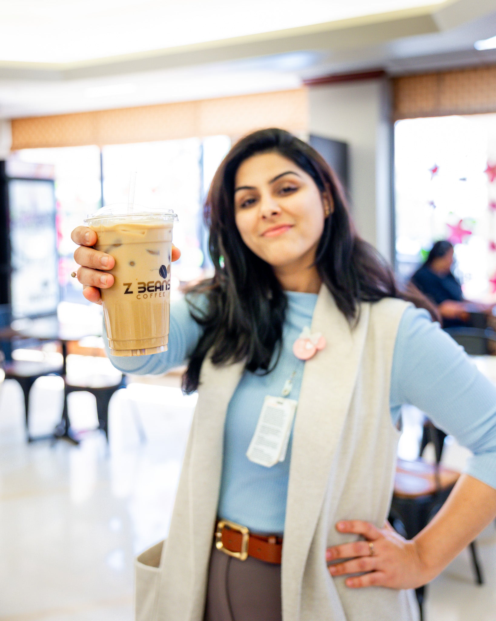 Woman holding a Z Beans coffee drink in a coffee shop setting