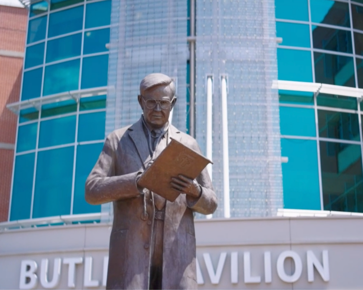 Statue of a man in a suit holding a document in front of a hospital building with 'Butler Pavilion' sign.
